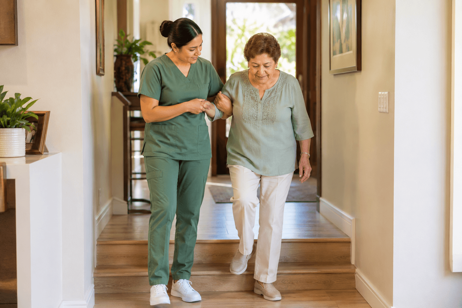 Jane's Home Care caregiver offering a steady arm to a senior walking down hallway steps in her Fresno home